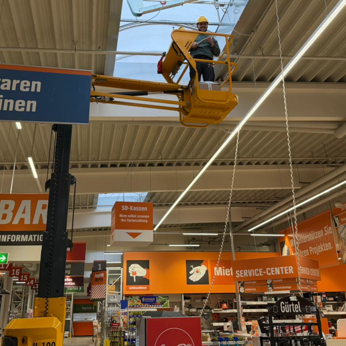Brandschutztechniker auf Hubarbeitsbühne bei der Wartung von Brandschutzanlagen im Einzelhandel
